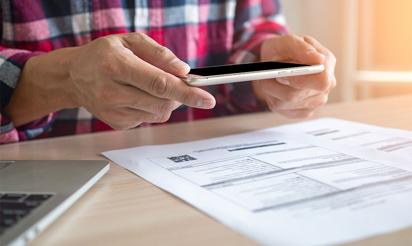 Hands holding a phone over a document on a table